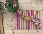 Striped clutch bag on a wooden surface with a plant in the background
