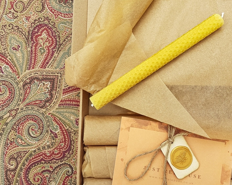 Rolls of brown paper and yellow candles on a patterned fabric background