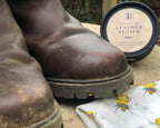 Pair of worn boots with a container of leather revive on a textured surface