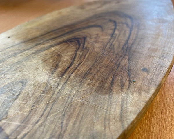 Close-up of a wooden cutting board with visible wear and tear