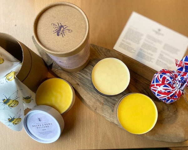 Collection of candles in various containers on a wooden surface with a Union Jack decoration.