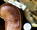 Leather care product on a leather armchair with a decorative cloth and small bag.